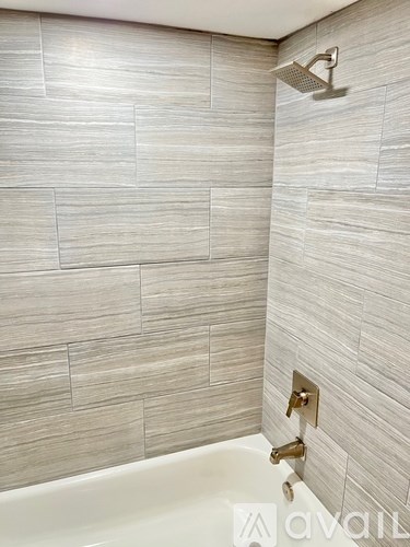 A bathroom with a white tub and a shower head.