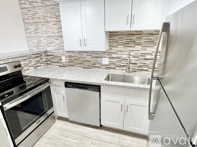 A kitchen with a stone backsplash and stainless steel appliances.