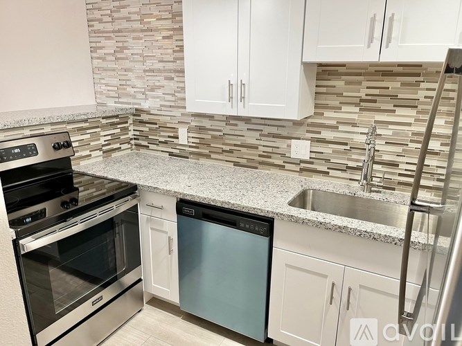 A kitchen with a stone backsplash and stainless steel appliances.