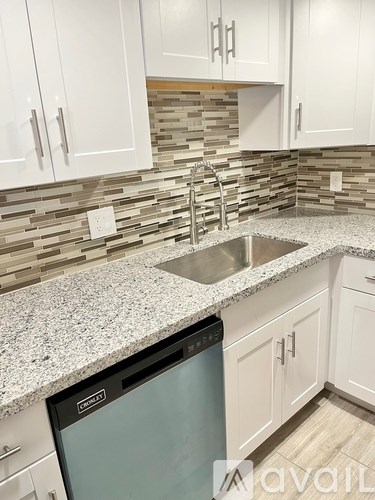 A kitchen with a granite countertop and a stainless steel dishwasher.