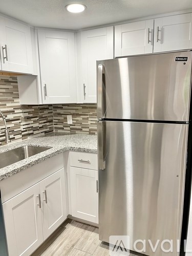 A stainless steel refrigerator in a kitchen with white cabinets.
