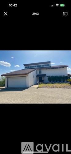 A white building with a brown roof and a garage door.