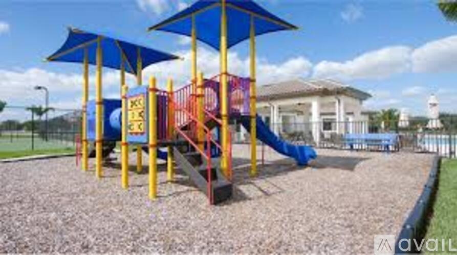 A playground with a blue umbrella and a slide.