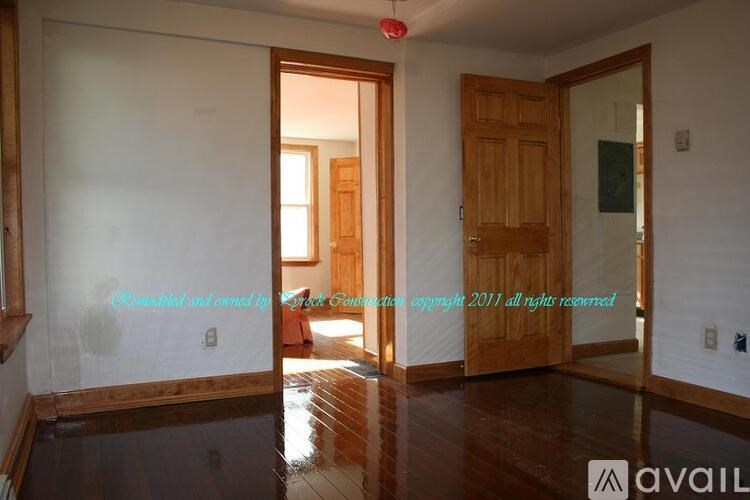 A room with a wooden floor and a door leading to another room.