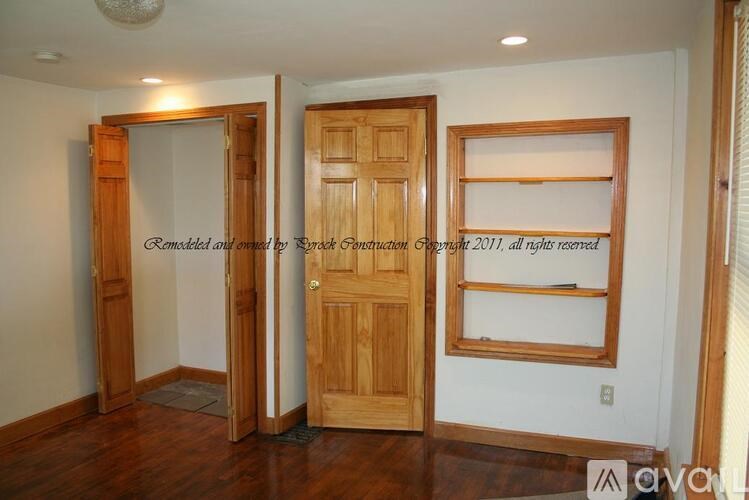 A room with a wooden door and a wooden shelf.