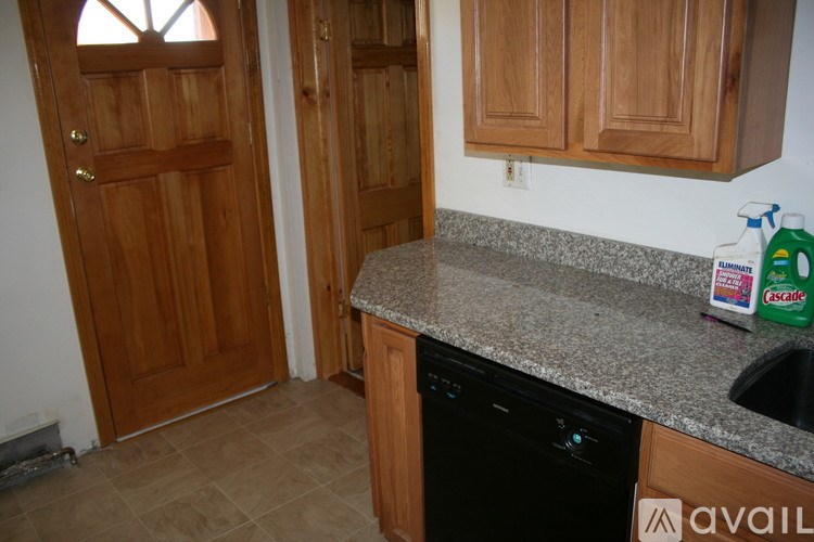 A kitchen with a black dishwasher and wooden cabinets.