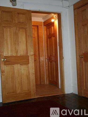 A wooden door with a brass handle is open to a hallway.