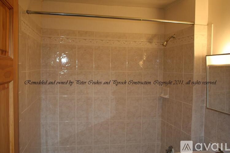 A bathroom with beige tiles and a shower area.