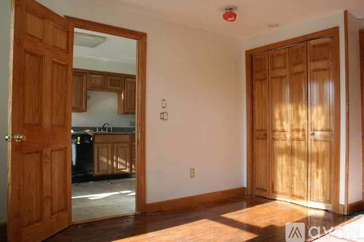 A room with a wooden door and a mirror on the wall.