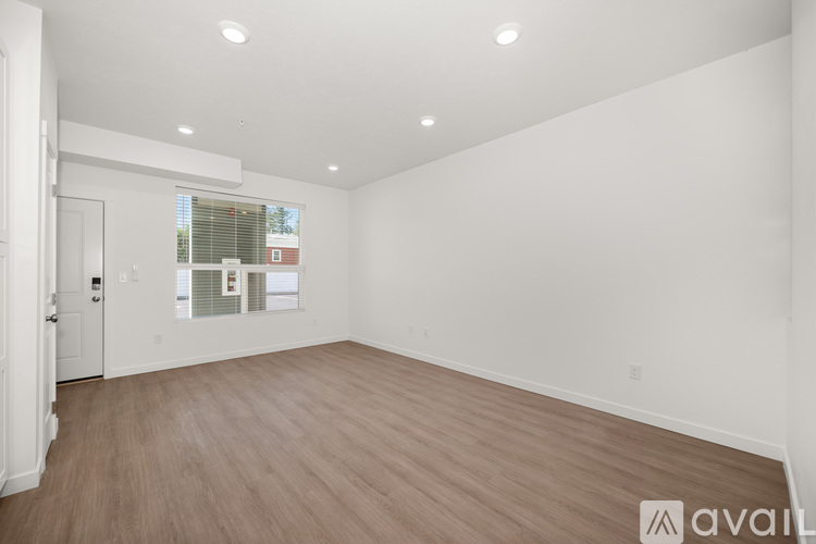 A spacious room with wooden flooring and white walls.