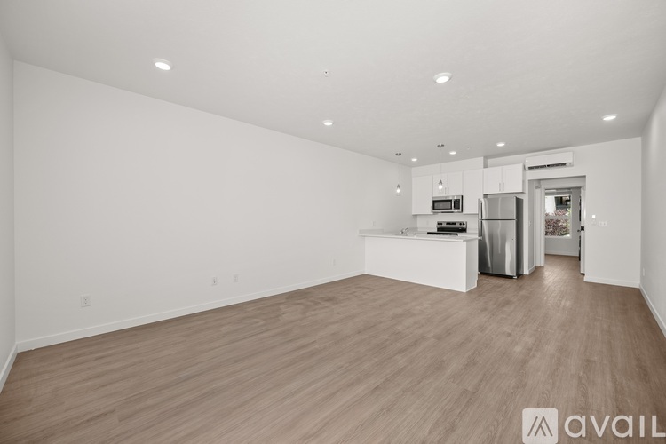 A spacious, empty room with wooden flooring and white walls.