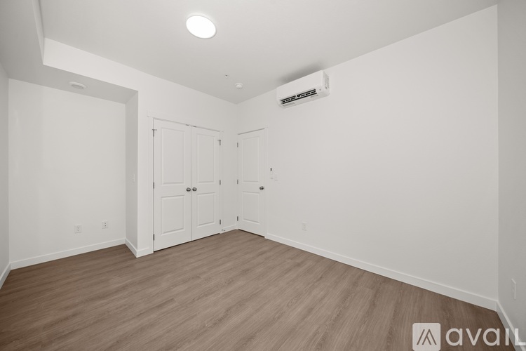 A room with a wooden floor and a white wall with a closed door.