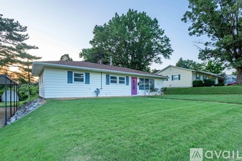 A house with a green lawn and trees in the background.