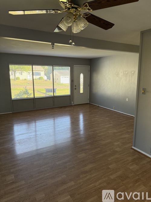 A room with a ceiling fan and wooden flooring.