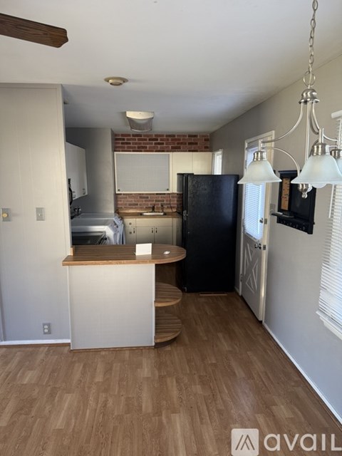 A kitchen with a black refrigerator and wooden floors.