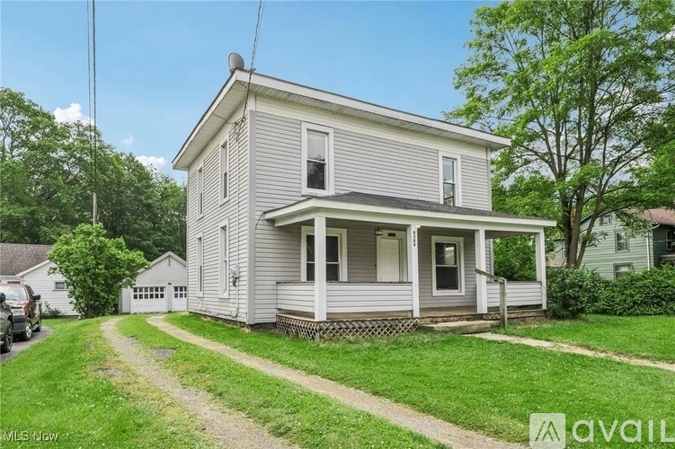 A house with a grey siding and a white door is for sale.
