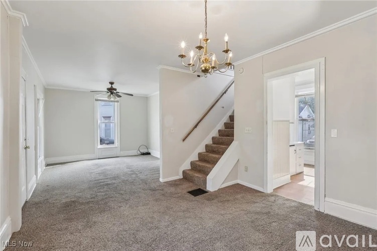 A spacious room with a staircase leading to the second floor.