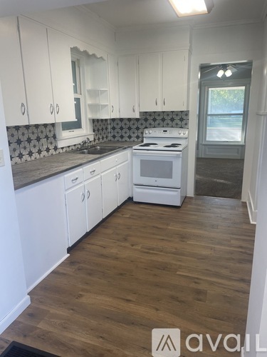 A kitchen with white cabinets and a wooden floor.