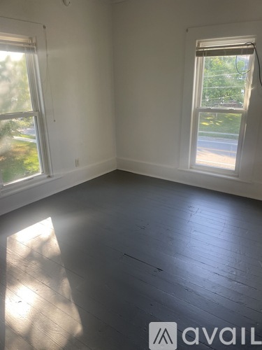 A room with white walls and a large window with a view of a street.