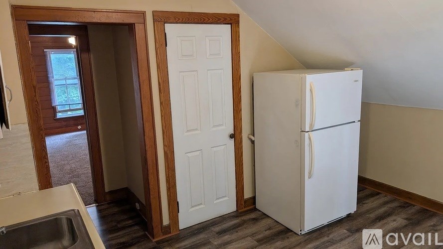 A white refrigerator is in a kitchen with a sink and a door.