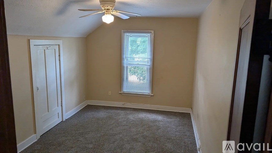 A room with a ceiling fan and a window with blinds.