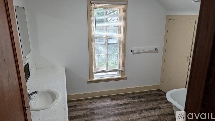 A bathroom with a white sink and brown floor.
