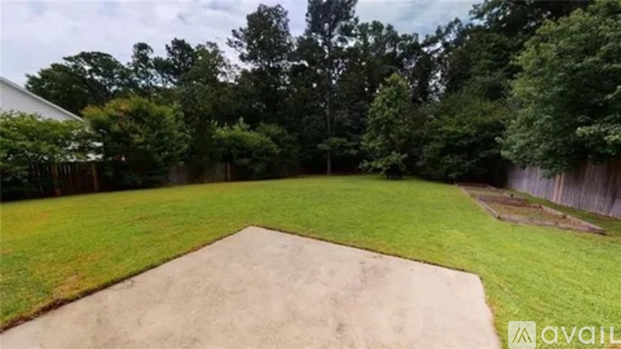 A backyard with a sand pit and a fence.