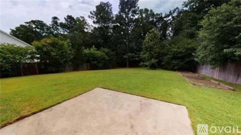 A backyard with a sand pit and a fence.