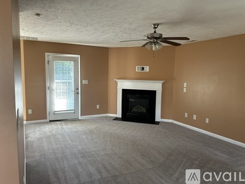 A living room with a fireplace and a ceiling fan.