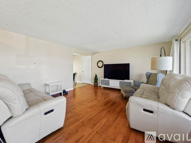 A living room with white furniture and a flat screen TV.