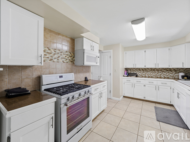 A kitchen with white cabinets and a tiled backsplash.