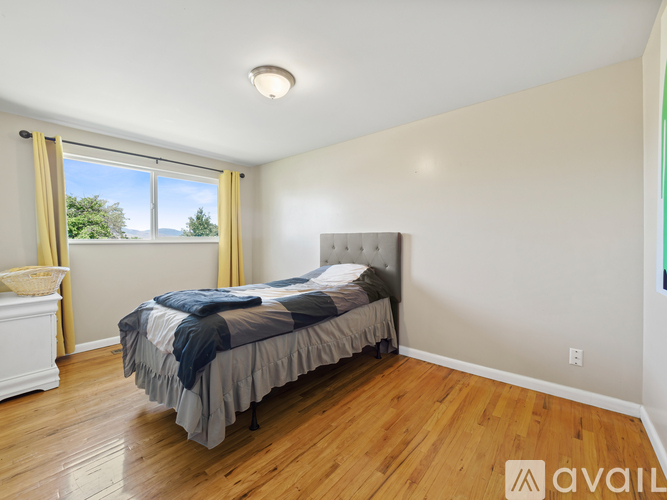 A bedroom with a large bed and a window with yellow curtains.