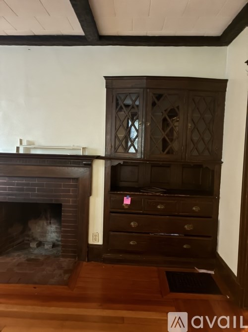 A dark brown wooden cabinet with glass doors is above a fireplace.