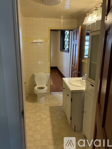 A bathroom with a toilet, sink, and wooden cabinets.