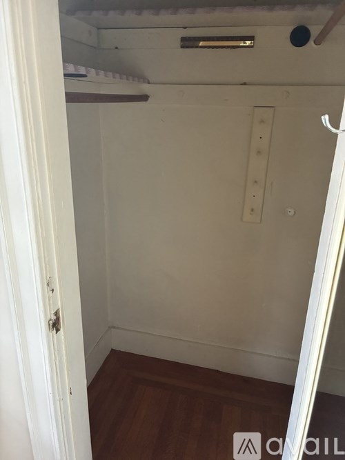 A small, empty room with a wooden floor and white walls.