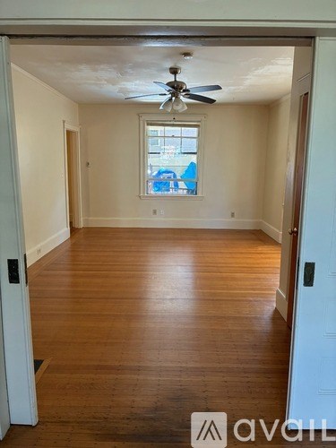 A room with wooden floors and a doorway leading to another room.