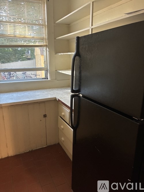 A black fridge in a kitchen with a window.