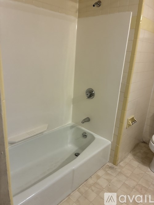 A white bathtub in a bathroom with a shower head.