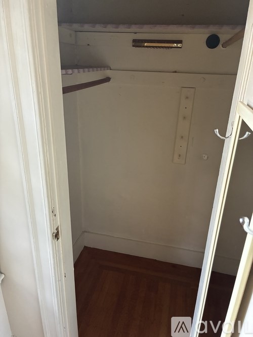 A small, empty room with a wooden floor and white walls.