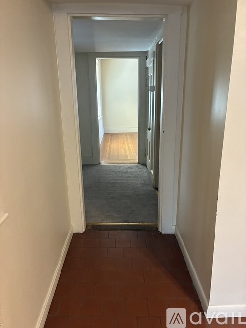 A hallway with a carpeted floor and white walls.