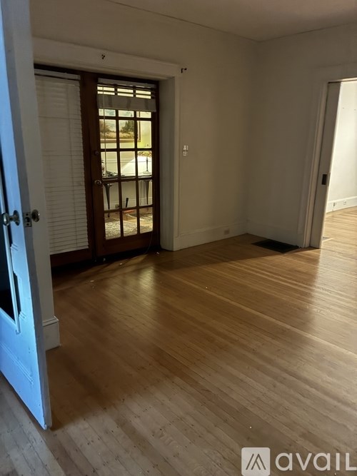 A room with wooden flooring and a door leading to a balcony.