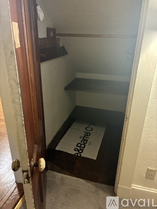 A small room with a wooden door and a white wall.