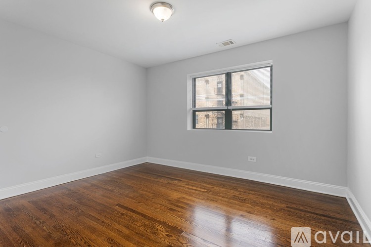 A room with wooden flooring and a window showing a view of a building outside.