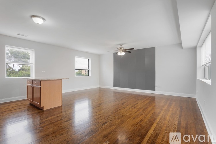 A spacious room with wooden floors and a ceiling fan.