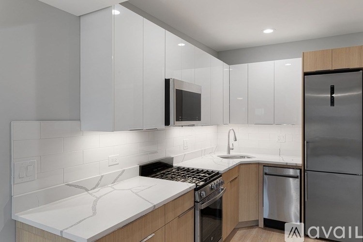 A modern kitchen with a white countertop and stainless steel appliances.