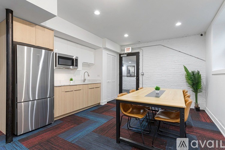 A kitchen with a refrigerator, microwave, and a dining table with chairs.