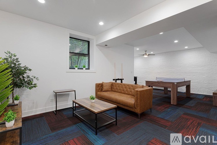 A living room with a brown sofa, a glass coffee table, and a white brick wall.