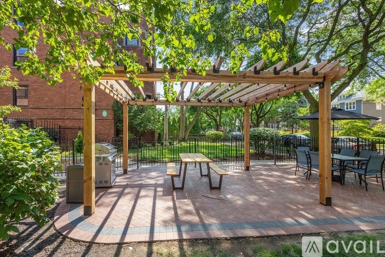 A wooden pergola is over a picnic table in a courtyard.