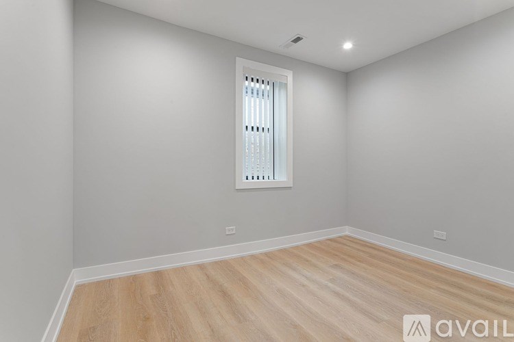 A room with wooden flooring and a window with blinds.