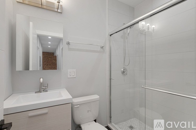 A bathroom with a white toilet, sink, and shower.